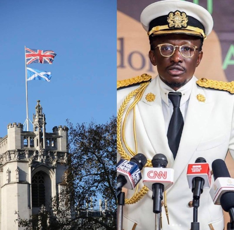 a man in a white suit and hat stands in front of a building with a flag
